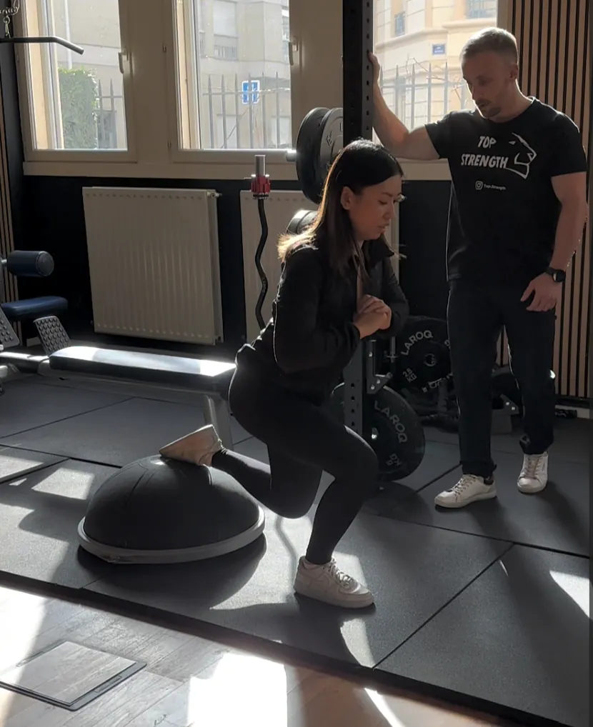 Fente et travail d'équilibre sur Bosu avec un coach, au studio Top Strength à Lyon 6